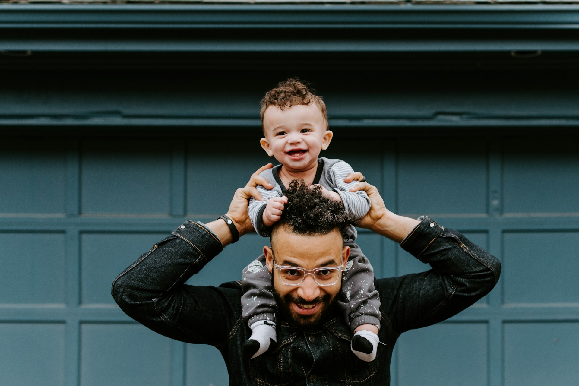 An image of a man holding his infant son on his shoulders.
