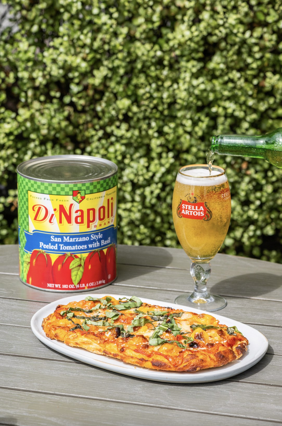 An image of a cold Stella Artois paired with a mouthwatering Centennial Flatbread made with San Marzano tomato sauce, cherry tomatoes, fresh mozzarella, and basil