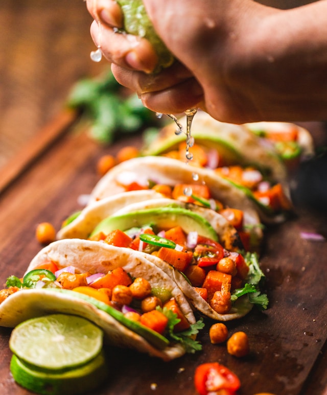 An image of someone squeezing fresh lime on tacos.