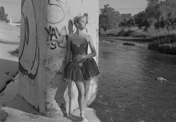 An image of a woman infront of a tagged bridge.