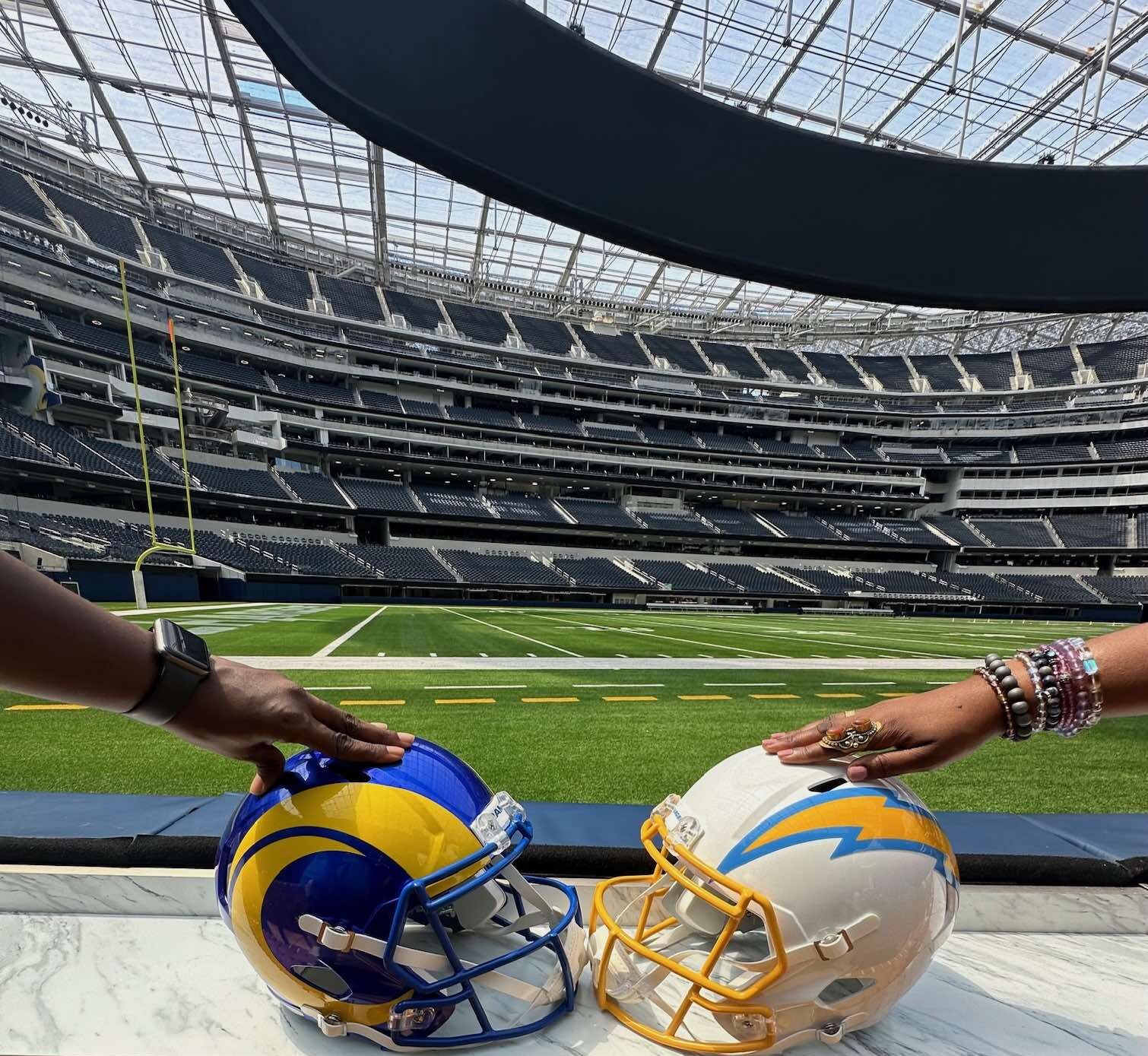 An image of two hands holding Chargers and Rams helmets.